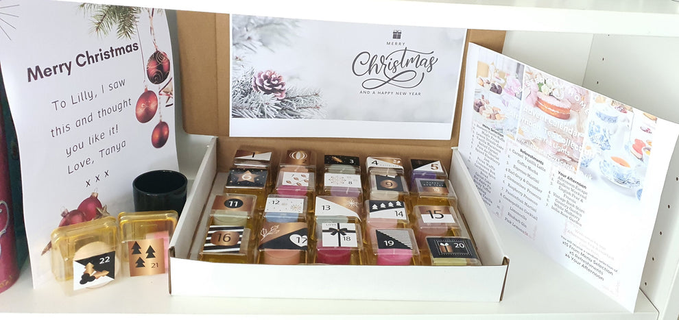 Box of Christmas-themed candles with cards and a candle holder  on a white surface