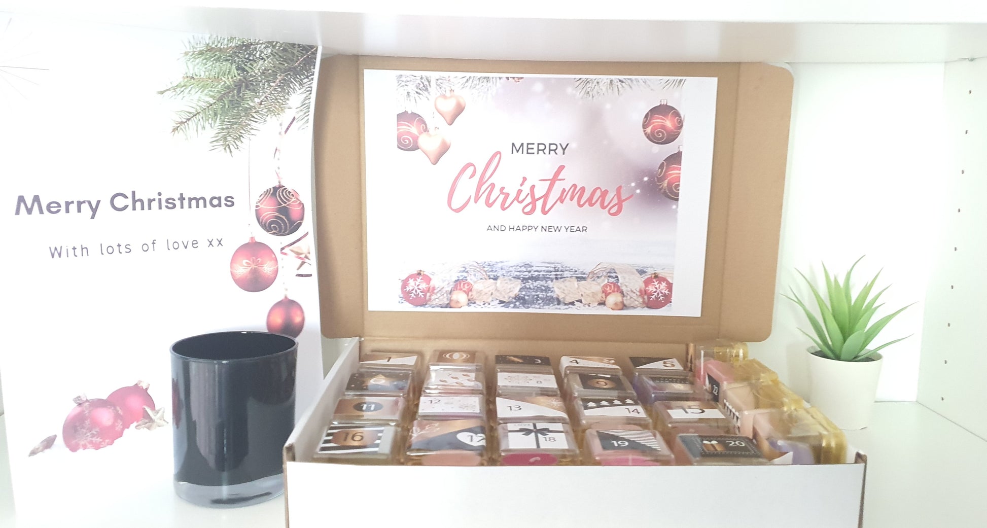 Box of tealight candles with a 'Merry Christmas' card on a white background