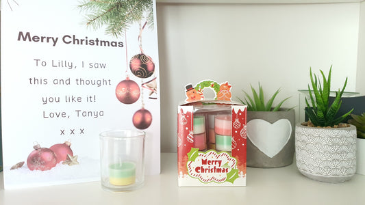 Christmas-themed gift box with candles and a card on a white surface