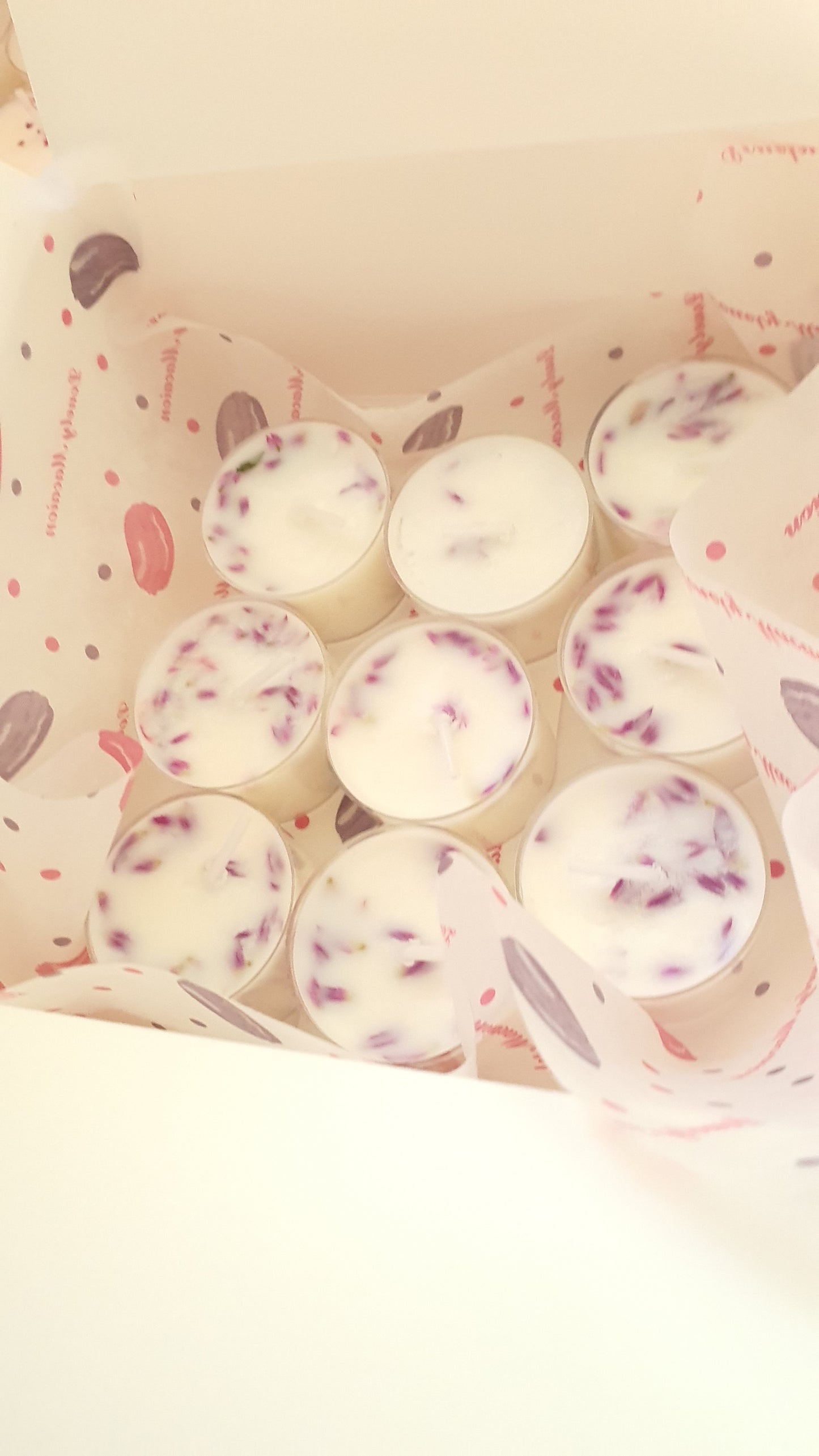 Set of small white candles with pink hearts in a pink container on a light beige background