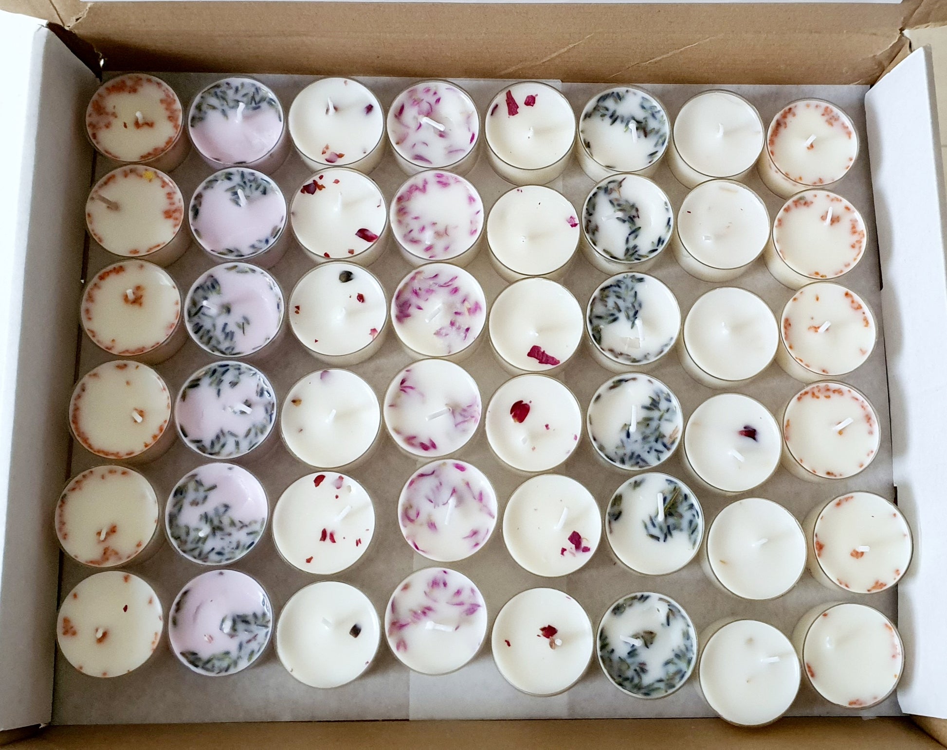 Assorted small candles in a cardboard box