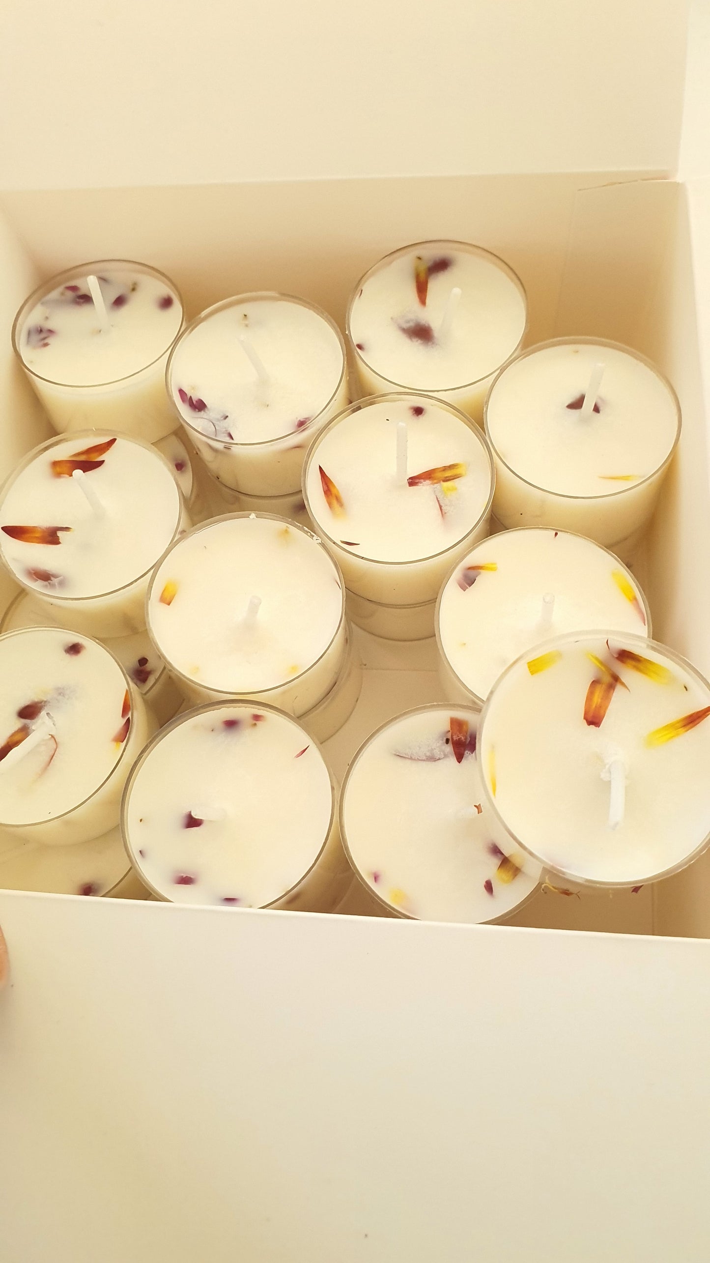 Box of small candles with floral candles on a light background